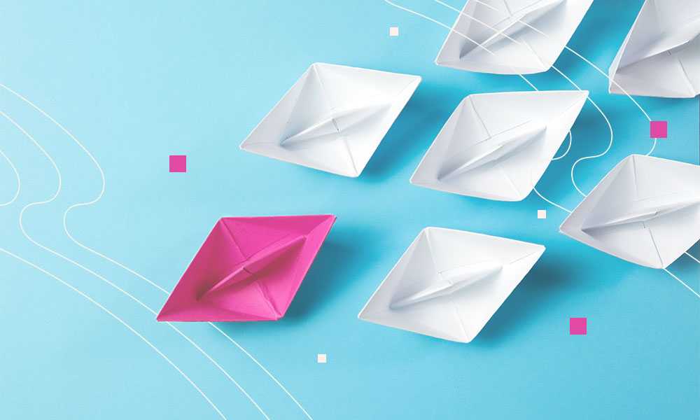 Image of white paper boats following a pink paper boat